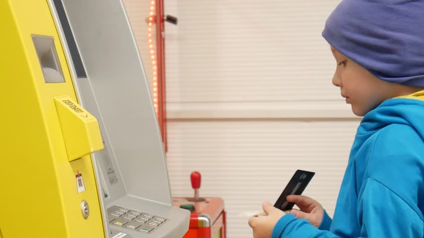 A cute boy inserts a bill into the ATM bill acceptor Royalty-Free Stock Footage #1110378065