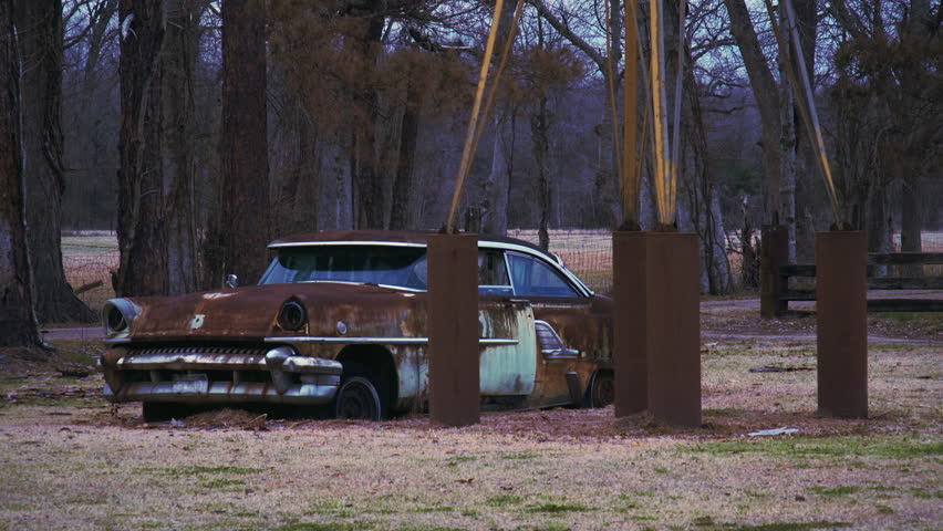 Old abandoned rusty car parked in grass. 