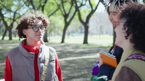 Group of young positive college friends discussing study while standing outdoors in the park. Medium shot - Powered by Shutterstock - Get 15% off with code: PIKWIZARD15