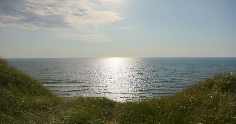 Wide shot of Lake Michigan with sand dunes in foreground on a sunny day.