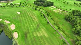 A sprawling golf course, a lush carpet of green fairways and manicured bunkers, surrounded by serene water hazards, all seen from a bird's-eye view.

