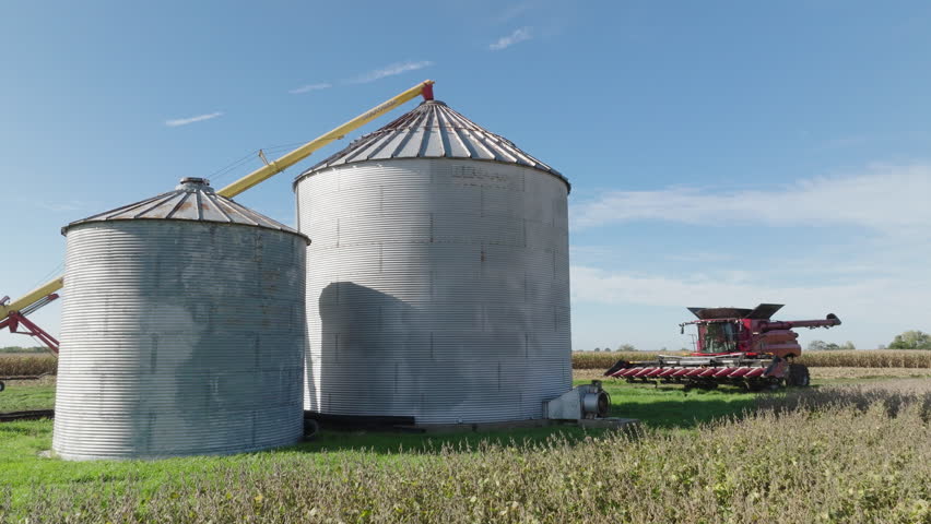 Grain Bin Silos and Combine Harvester in a Rural Farm Field, Aerial Royalty-Free Stock Footage #1110391419