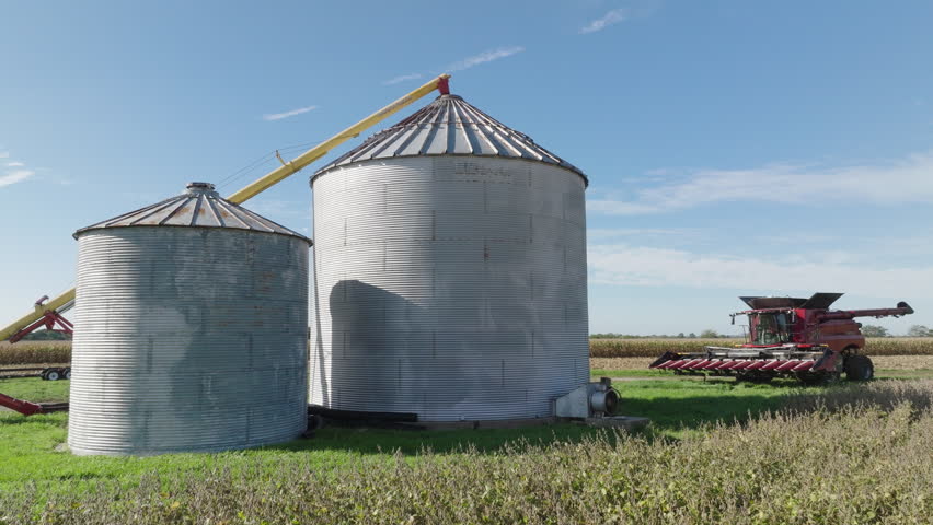 Grain Bin Silos and Combine Harvester in a Rural Farm Field, Aerial Royalty-Free Stock Footage #1110391641