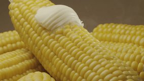 Piece of butter is slowly move along the ripe boiled cob of corn. Nice food background for your projects. Macro video shooting. 
