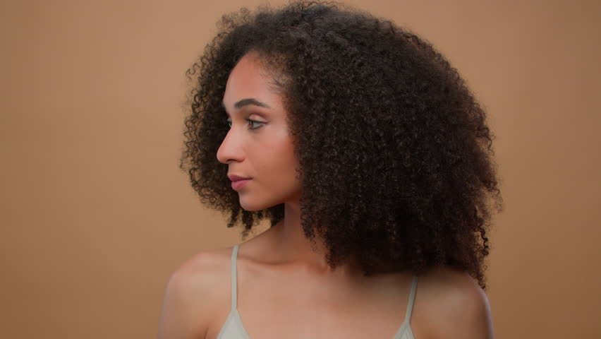 Portrait in studio beige background ad backdrop advertise mock up beautiful African American woman ethnic young attractive girl with curly hair perfect skin care make up beauty posing smiling cosmetic