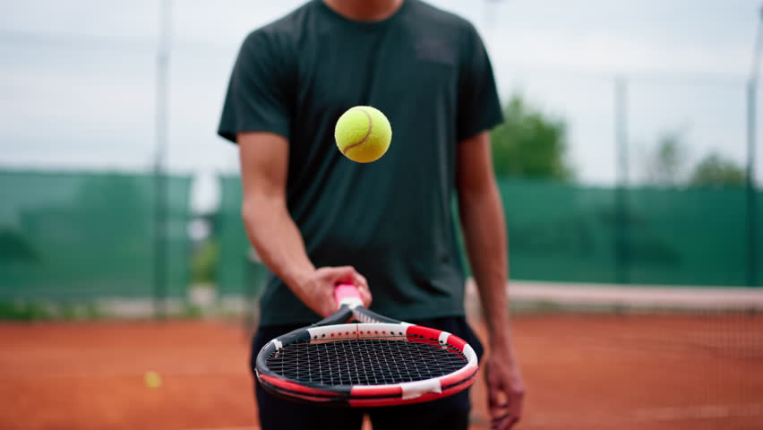 close-up young tennis player trainer hitting the ball with a racket on the tennis court preparing for the competition sports lifestyle