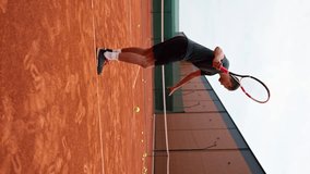 vertical video young professional player coach on outdoor tennis court practices strokes with racket tennis ball
