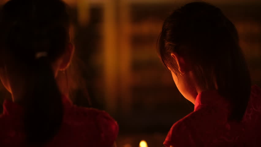 Happy Asian family, mother and children lighting candles to paying homage Buddha in temple to make a wish on the traditional Songkran festival in Thailand.