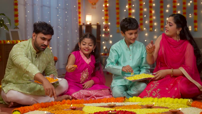 Joyful Indian Young parents with kids preparing diwali rangoli for festival celebration at home - concept of holidays reunion, traditional custom or rituals and family bonding