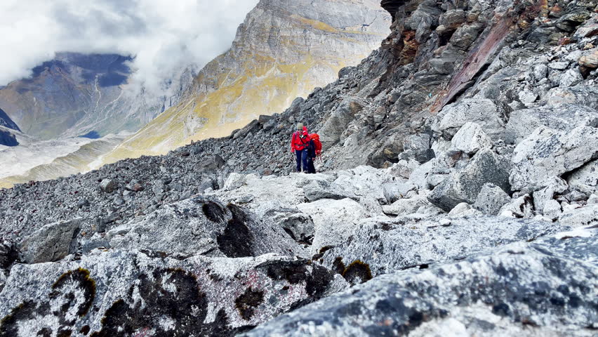 Two expedition members with backpacks together following Makalu Barun Park trekking route near Khare. Mera peak climbing acclimatization walk. Backpackers using trekking poles, enjoying valley view. Royalty-Free Stock Footage #1110413151