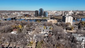 Aerial video of Saskatoon's downtown central business district, SK, Canada. Skyline view reveals bustling urban life, commercial buildings, and roads. Ideal for business concepts.