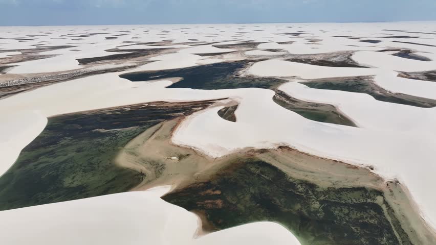 Aerial view of Parque Nacional dos Lencois Maranhenses, a protected coastal area of sand dunes and salt marsh with numerous ponds and lagoons, Barreirinhas, State of Maranhao, Brazil. Royalty-Free Stock Footage #1110416889