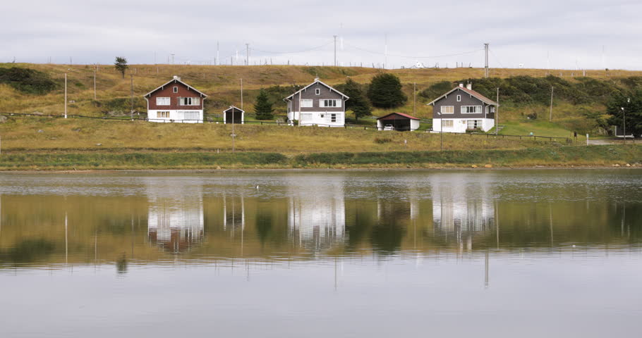 View of three coastal houses in the seashore and their reflection in water