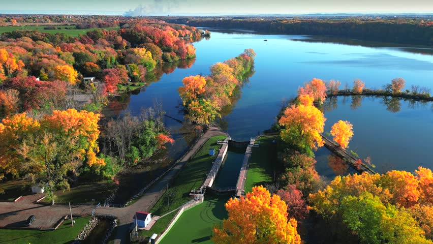 Amazing peak Fall colors by the riverside mid October in Wisconsin, moving aerial view.