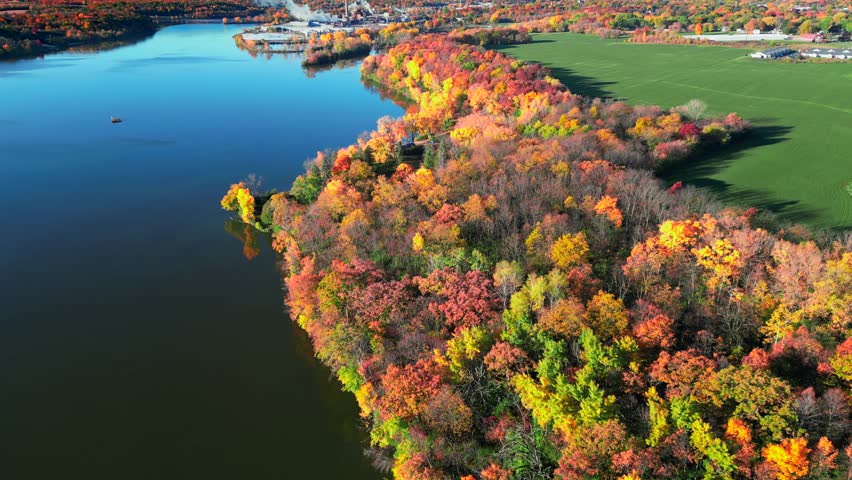 Amazing peak Fall colors by the riverside mid October in Wisconsin, moving aerial view.