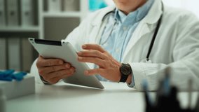 A specialist doctor dressed as a medical employee concentratesly holds a tablet in his hands and looks at the screen in the office. A clinic worker works with an electronic tablet and looks at data. - Powered by Shutterstock - Get 15% off with code: PIKWIZARD15