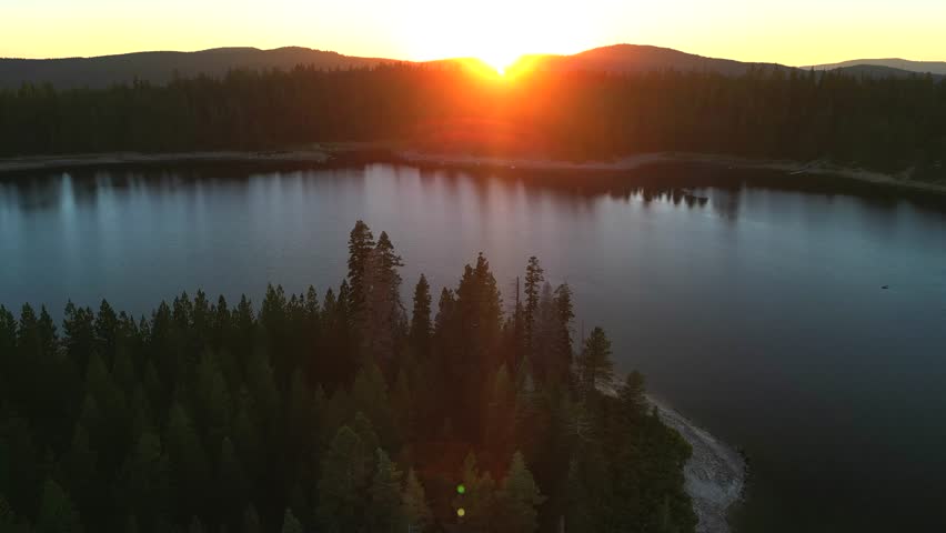 Drone flight in cinematic mode above lake with pine forest around. Usa national park area | Shutterstock HD Video #1110432329