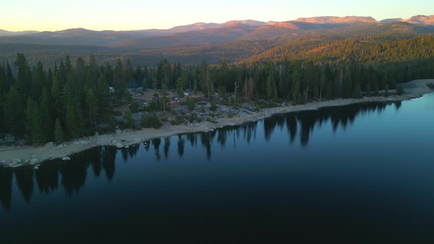 Drone flight in cinematic mode above lake with pine forest around. Usa national park area | Shutterstock HD Video #1110432331