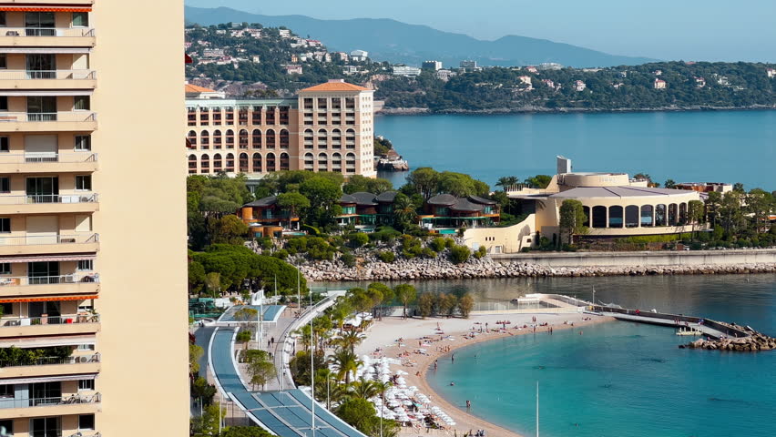Vertical footage of famous beach of principality of Monaco in sunny day, Italia is on background, new construction, azure water