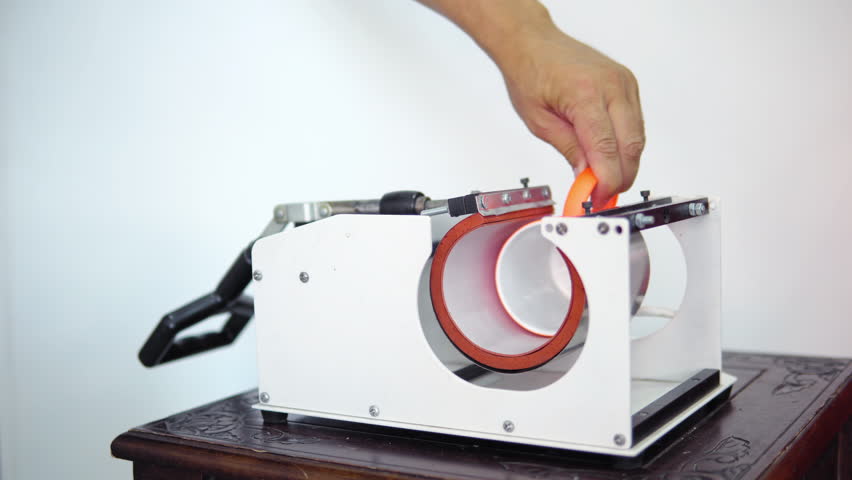 Man putting mug in a thermopress for cup print - intended for transfer image or a logo on a mug, cup