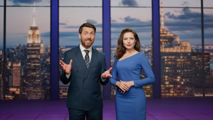 Friendly anchors smiling in studio television channel. Cheerful couple newsreaders reporting breaking news together lighting current information. Bearded anchorman talking to happy anchorwoman. Royalty-Free Stock Footage #1110436651