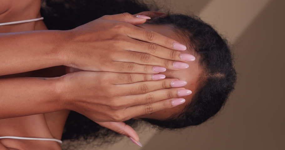 Vertical clip. Portrait of a black girl with curly hair, soft makeup and perfect skin. Beautiful face of young black woman with natural skin.