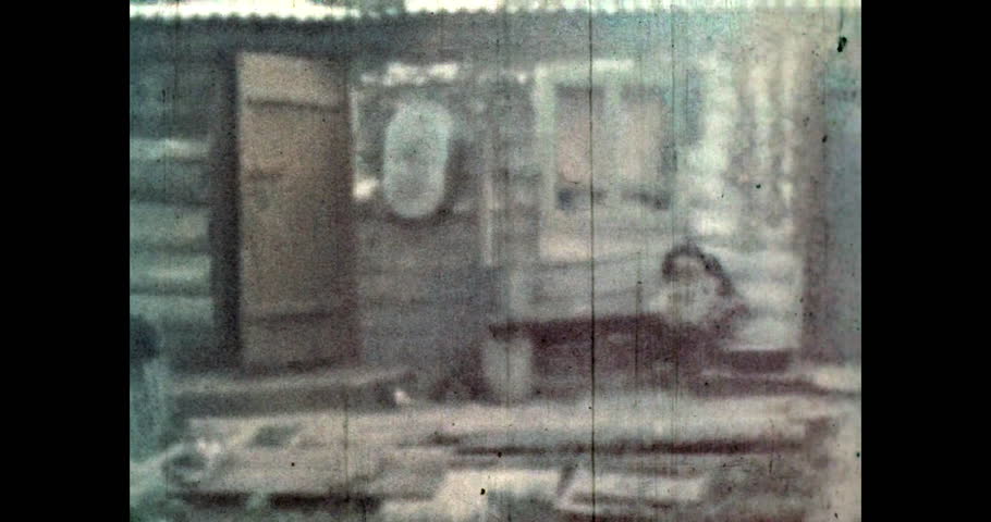 Woman washes her hands in front of porch house. Wooden rural house, facade. Ukraine 1960s, archive, film