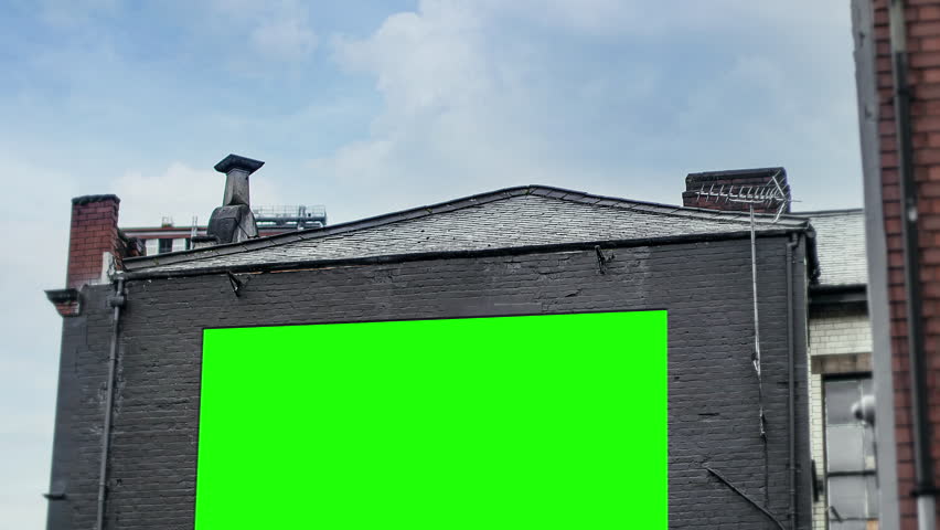 Building Outdoor Billboard Green Screen Panel Cloudy Sky Tilt Down. A large green screen billboard panel, for replacement, outdoor on a building wall. Tilt down Royalty-Free Stock Footage #1110448731