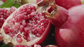 Ripe pomegranate fruits with slices and pomegranate tree leaves slowly move in the frame on a gray stone table. Nice fruit background for your projects. Macro video shooting. - Powered by Shutterstock - Get 15% off with code: PIKWIZARD15