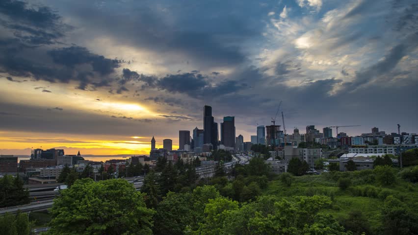 Timelapse of moving clouds and dramatic sunset over the Seattle downtown skyline, with traffic on the I-5 and I-90 freeway interchange, viewed from Dr. Jose Rizal Bridge. 4K UHD video.