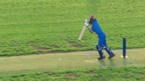 Portrait of a Professional Cricket Player in Blue Uniform and Protective Helmet Practicing to Hit the Ball During Training. Batsman Warming Up Before a Championship Match - Powered by Shutterstock - Get 15% off with code: PIKWIZARD15