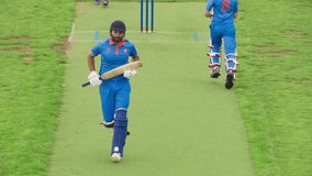 Professional Indian Cricket Player Striking the Ball to the Outfield. Both Batters Successfully Finishing Their Both Scoring Runs. TV Match Broadcast of Professional Cricket Game - Powered by Shutterstock - Get 15% off with code: PIKWIZARD15