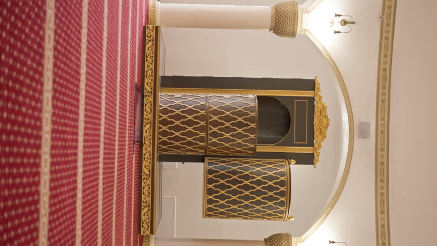 Large empty prayer hall with red carpet and large windows before Islam believers praying in a Muslim mosque
