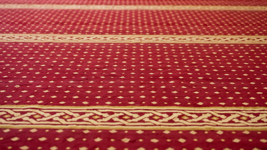 Large empty prayer hall with red carpet and large windows before Islam believers praying in a Muslim mosque