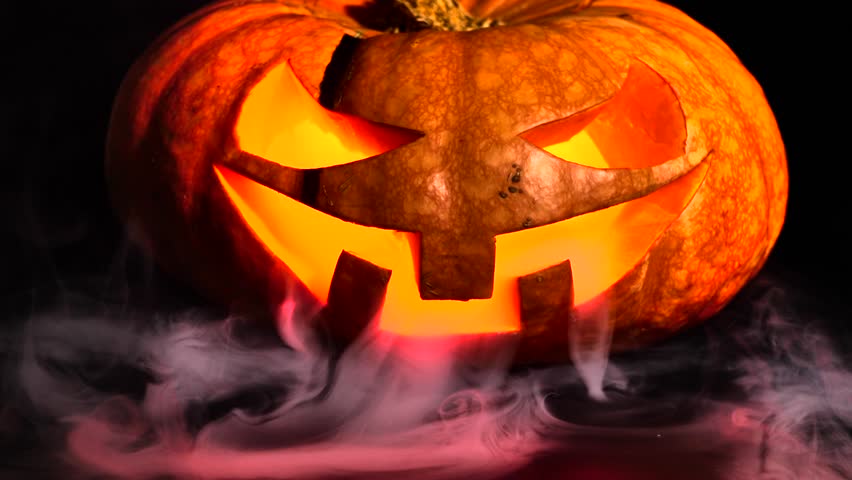Halloween pumpkin in smoke. Halloween pumpkin smile and scary eyes for party. Close up view of a scary Halloween pumpkin with eyes glowing inside on a black background. Selective Soft Focus | Shutterstock HD Video #1110481431