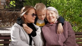 Portrait of a happy grandmother with her daughter and grandson in the park on a bench, a boy embracing his grandmother and mother. Happy family in the city park, family meeting. - Powered by Shutterstock - Get 15% off with code: PIKWIZARD15