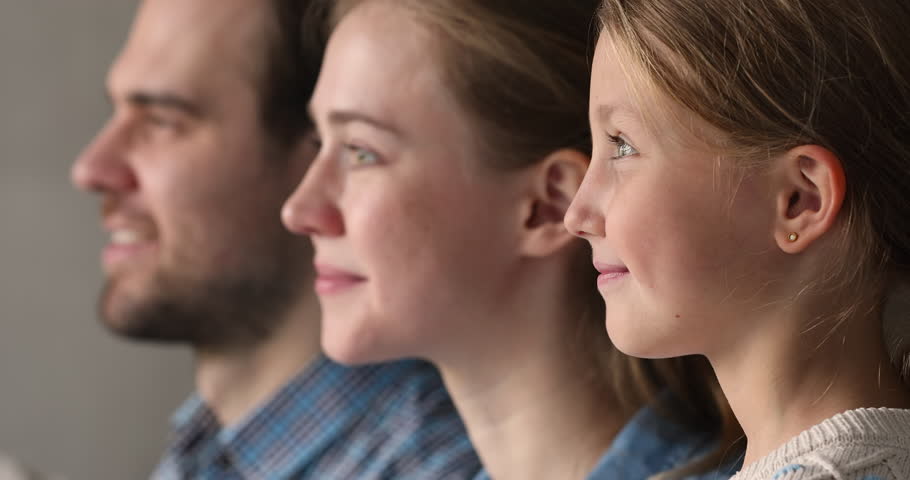 Side view happy millennial couple parents and little child girl standing in row looking forward turning heads to camera by one. Close up profiles of mother father preteen daughter kid smiling faces Royalty-Free Stock Footage #1110482485