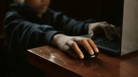 Asian boy uses a laptop computer with a serious expression.