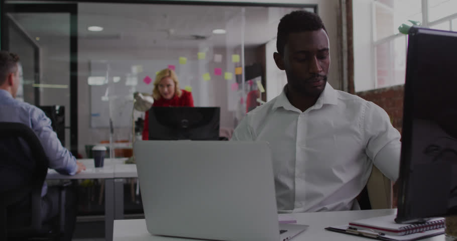 Animation of big data text over african american man talking on cellphone while working on laptop. Digital composite, multiple exposure, business, data set, office and technology concept.