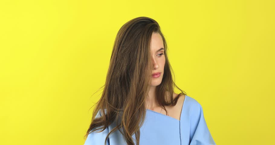 Close up of annoyed irritated young woman with an angry face looking furious, mad and feeling frustrated isolated on yellow background. Brunette girl expressions and emotions, wear blue sweater. Royalty-Free Stock Footage #1110495945