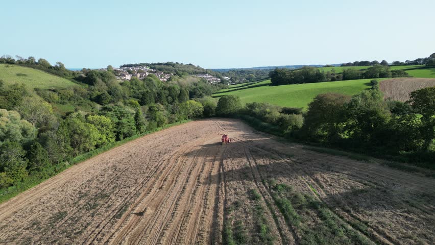 Blagdon, Torbay, South Devon, England: DRONE VIEWS: The drone gives an overhead view of a mechanised ploughing machine as it ploughs an overgrown farm field, a task traditionally done in the autumn. Royalty-Free Stock Footage #1110501001