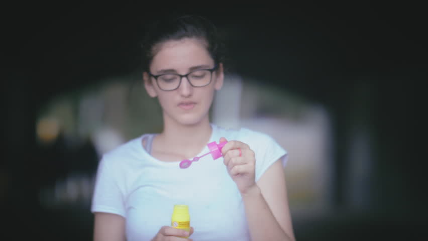 Bubbly Fun: Young Girl Blowing Soap Bubbles on a Gloomy Day