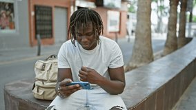 African american man watching soccer game on smartphone celebrating at street - Powered by Shutterstock - Get 15% off with code: PIKWIZARD15