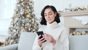Happy excited young woman received great news on smartphone while sitting on sofa at home during winter New Year Christmas Xmas holidays. Girl reads a pleasant message on the phone, celebrates success - Powered by Shutterstock - Get 15% off with code: PIKWIZARD15