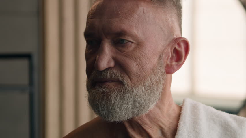 Close up old Caucasian elderly male senior happy smiling toothy mature retired pensioner 60s man naked with bath towel on shoulder smile dental in bathroom indoors at home hotel skincare wrinkled face