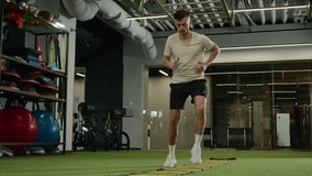 Caucasian sportsman man footballer soccer player training in sports gym exercise with ladder sport equipment workout cardio exercising jumping prepare for football match male athlete in fitness club - Powered by Shutterstock - Get 15% off with code: PIKWIZARD15