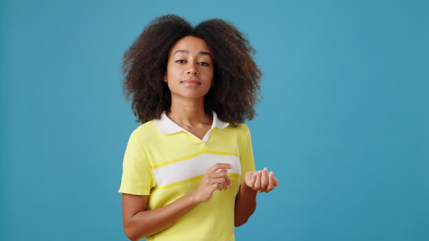 African-American woman counts on fingers on blue background. Thoughtful black lady marks solved tasks and shows thumb up in studio. To do plan Royalty-Free Stock Footage #1110515411