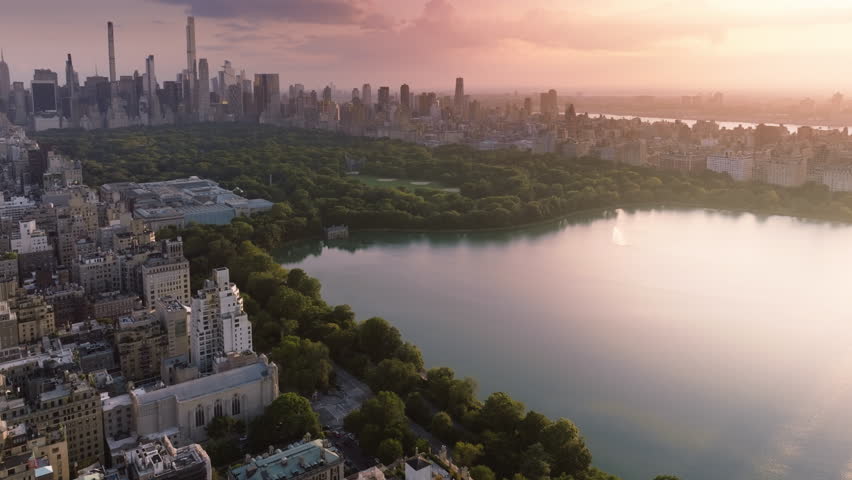 Green urban Central park aerial. 4K epic panorama of Manhattan. New York city downtown background. Urban park summer travel. Epic pink sunset above Central park. Scenic lake reflecting beautiful sky Royalty-Free Stock Footage #1110518419