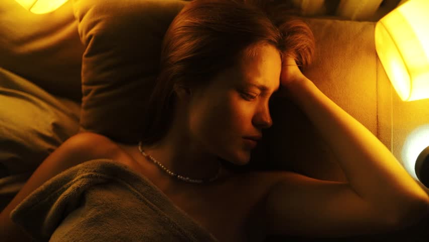 young woman in bed crying and suffering from insomnia and nightmares, mental illness sleep disorder.