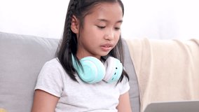 Addicted internet social media connection with modern technology laptop little elementary school children chatting sitting on sofa, happy emotional Asian cute girl kids have fun talk to friends online